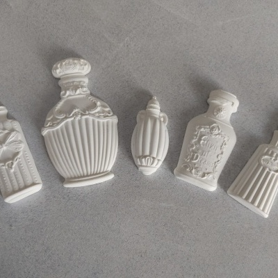 Cinco frascos decorativos em cerâmica branca sobre superfície cinzenta.