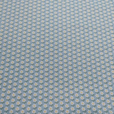 Tecido azul claro com pequenas flores brancas e amarelas em padrão repetido