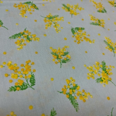 Tecido branco com padrão de flores amarelas e folhas verdes.