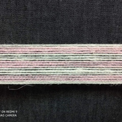 Fios de lã ou algodão em tons pastel alinhados sobre tecido preto.