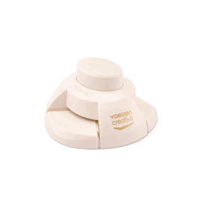 Aparelho branco com botões circulares em camadas e texto 'vaessen creative'