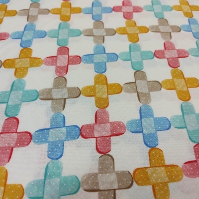 Tecido branco com padrão colorido de cruzes ovais com bolinhas