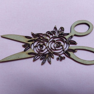 Tesoura decorativa em madeira com padrão floral sobre fundo rosa