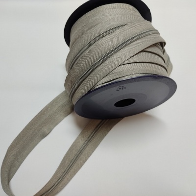 Rolo de fita zíper bege enrolado num carretel preto