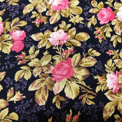 Tecido com padrão floral rosa e folhas verdes sobre fundo preto.