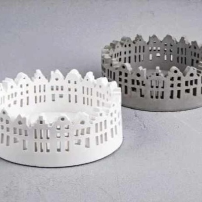 Castiçais redondos em cerâmica branca e cinzenta com padrão de casas recortadas.