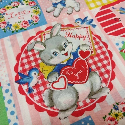 Tecido com desenho de coelho segurando corações e pássaros, com padrões florais e xadrez