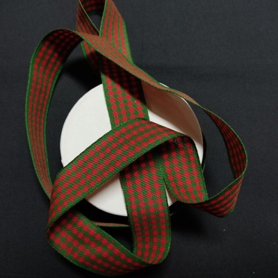 Fita decorativa xadrez vermelho e verde enrolada em caixa redonda branca