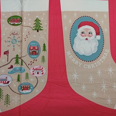 Sacos de tecido natalícios com desenhos do Pai Natal e mapa de Natal, fundo bege e bordas vermelhas.