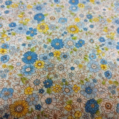 Tecido branco com padrão de flores azuis, amarelas e castanhas