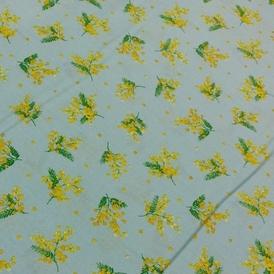Tecido azul claro com padrão de flores amarelas e folhas verdes