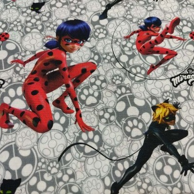 Tecido estampado com personagens vermelhos e pretos com bolinhas e texto Be Miraculous