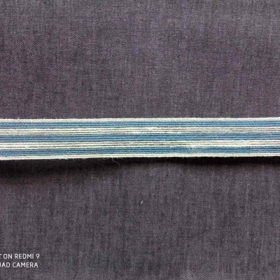 Tira de tecido elástico azul, branco e cinzento sobre tecido cinzento escuro