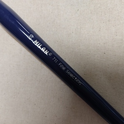 Caneta azul escuro com texto MILAN 711 Fine Selection sobre fundo de tecido bege