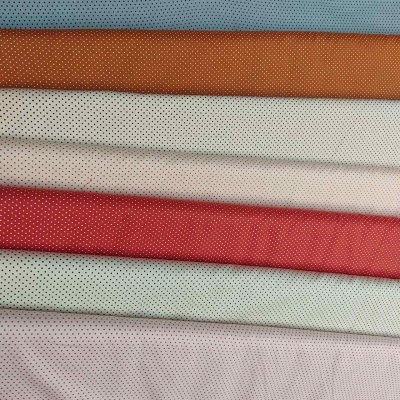 tecidos dobrados em várias cores com padrão de pequenos pontos pretos
