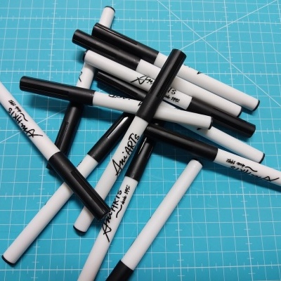 Marcadores brancos e pretos com texto manuscrito sobre superfície azul quadriculada