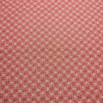 Tecido vermelho com padrão floral e régua para medição sobre madeira