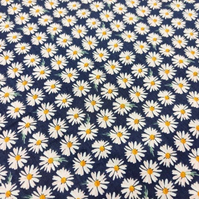 Tecido com padrão de margaridas brancas e amarelas em fundo azul escuro