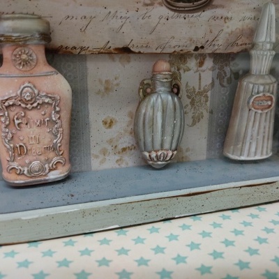 Três frascos decorativos emoldurados em vidro e madeira cinzenta com fundo manuscrito