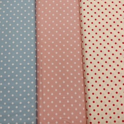 Três tecidos com padrão de bolinhas em azul claro, rosa claro e bege com vermelhas