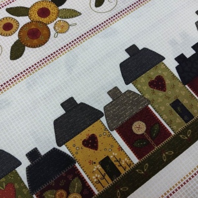 Tecido decorativo com casas estilizadas, flores e abelhas em cores quentes sobre fundo branco quadriculado