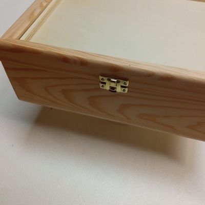 Caixa de madeira clara com fecho metálico dourado vista de perto