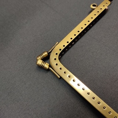 Moldura metálica dourada com orifícios e mecanismo de ajuste