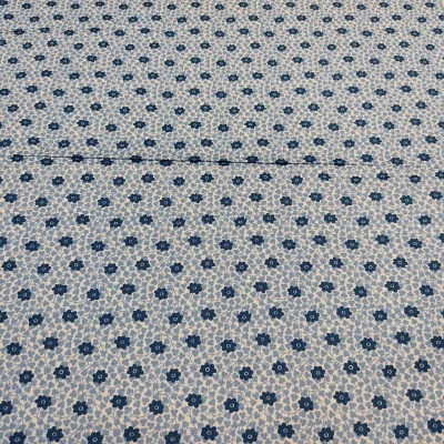 Tecido branco com pequenas flores azuis escuras e detalhe azul claro