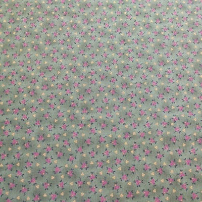 Tecido verde claro com pequenas flores cor-de-rosa, lilás e amarelas
