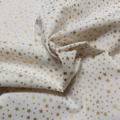 Tecido branco com pequenas estrelas douradas