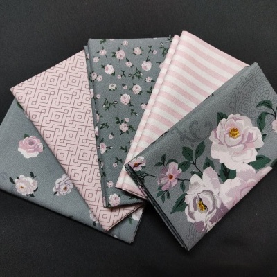 Tecidos dobrados com padrões florais e listras em verde-acinzentado e rosa