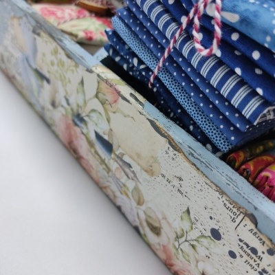 Tecidos azuis com padrões variados numa caixa decorativa floral