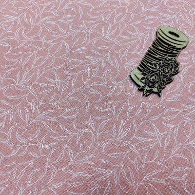 Tecido cor de rosa com padrão de folhas brancas e objeto decorativo de madeira em forma de carretel