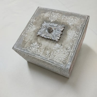 Caixa decorativa quadrada cinzenta com padrão floral branco e puxador central