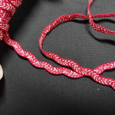 Fio têxtil trançado vermelho e branco sobre fundo preto