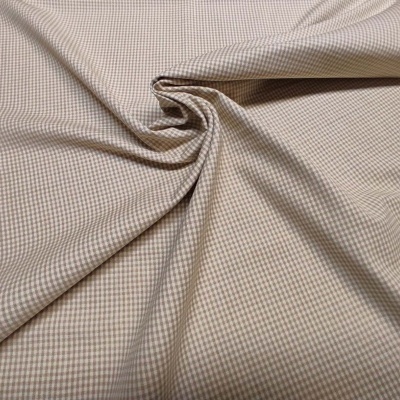 Tecido príncipe de gales em bege e castanho dobrado com padrão xadrez pequeno.