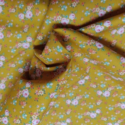 tecido amarelo mostarda com padrão de pequenas flores coloridas