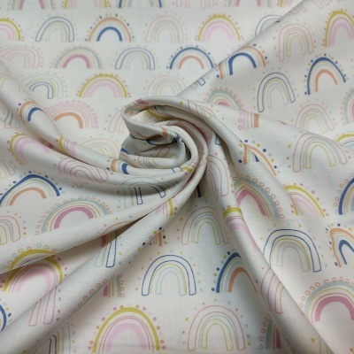 Tecido com padrão de arcos-íris em tons pastel enrolado sobre tecido similar