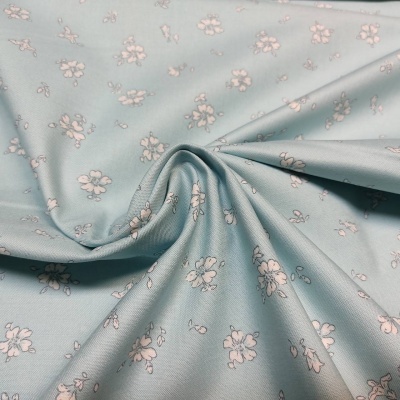 Tecido azul claro com pequenas flores rosas e textura suave