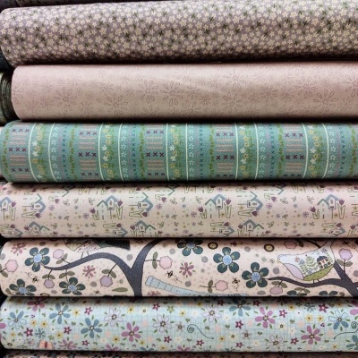 Tecidos com padrões florais coloridos em tons pastel sobrepostos numa pilha