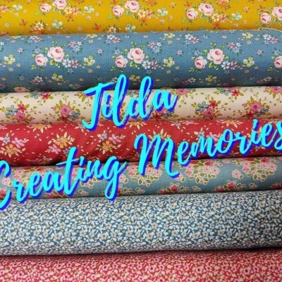 Pilha de tecidos florais coloridos e texto azul 'Tilda Creating Memories'