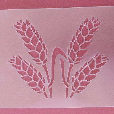 Stencil transparente com desenho de quatro espigas de trigo sobre fundo rosa