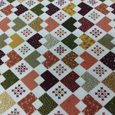 Tecido estampado com padrões geométricos coloridos em quadrados e losangos.