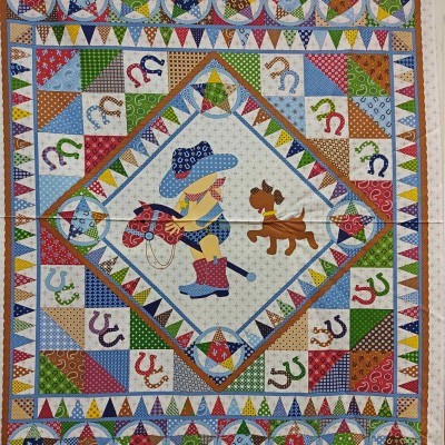 Colcha patchwork com figura central de cowboy criança e cão, ferraduras e triângulos coloridos.