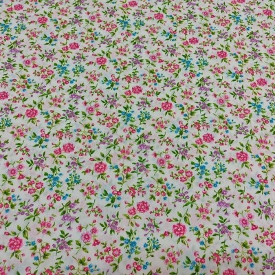Tecido branco com padrão floral pequeno rosa e azul com folhas verdes