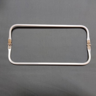 Estrutura rectangular de tecido bege com fechos dourados sobre fundo cinza