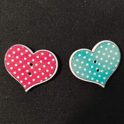 Dois botões em forma de coração, vermelho e azul claro com bolinhas brancas