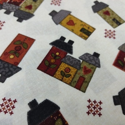 Tecido branco com padrão de casinhas coloridas e pequenos motivos vermelhos.