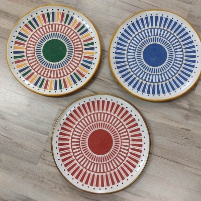 Três pratos redondos coloridos sobre chão de madeira clara
