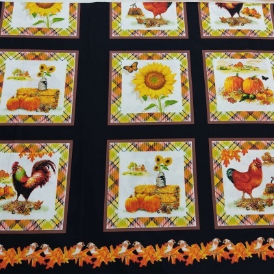 Tecido preto com padrão de quadrados e ilustrações de girassol, abóboras, galinhas e folhas de outono.